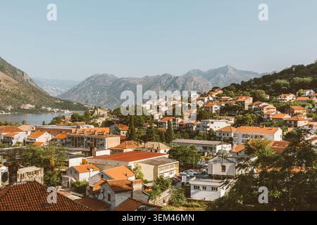 Ampia vista panoramica su Cattaro con tetti in terracotta, verdi colline e aspre montagne sopra la baia di Cattaro, Montenegro, in una giornata di sole limpido Foto Stock