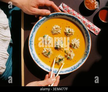 Persona che mangia gnocchi in zuppa da una ciotola in un ristorante himalayano Foto Stock