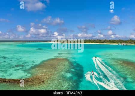 Vista aerea di un'isola tropicale esotica con la scia di una barca a motore su una laguna di barriera corallina. Mare turchese sabbia bianca. Paradiso per vacanze di lusso Foto Stock