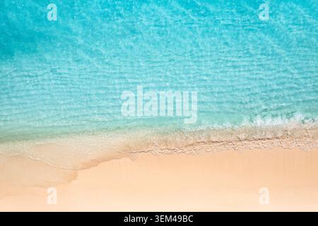 Vista aerea spiaggia mare turchese incontra sabbia dorata schiuma di onde bordo riva tropicale dall'alto. Modello paesaggio viaggio drone estate. Paradiso benessere Foto Stock