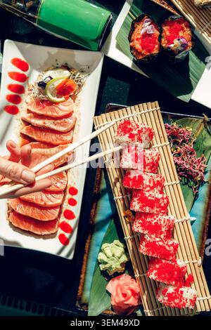 Persone in un sushi bar che mangiano sushi con bacchette. Foto Stock