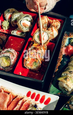 Persone in un sushi bar che mangiano sushi con bacchette. Foto Stock