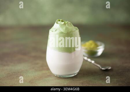 Dalgona Matcha latte, un matcha cremoso montato in bicchieri, su sfondo verde. Foto Stock