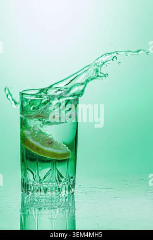 Un bicchiere d'acqua con limone. Primo piano su sfondo verde. Foto Stock