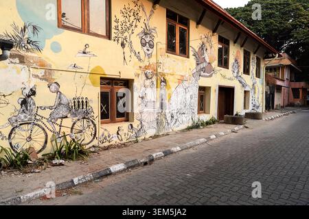 Vibranti murali di arte stradale contemporanea dipinti sulle facciate erose di edifici dell'era coloniale nelle strade storiche di Fort Kochi, India. Foto Stock