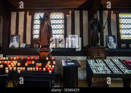 Interno della chiesa di Santa Caterina a Honfleur, che mostra statue di santa in legno e ritratti in bianco e nero su pareti incorniciate in legno. L'impresa in primo piano Foto Stock