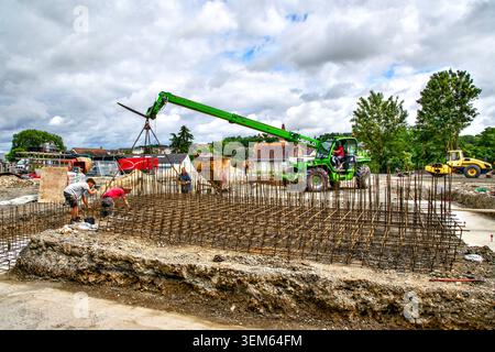 Merlo Telehandler che abbassa il rinforzo dei tondini nelle fondamenta del cantiere - Preuilly-sur-Claise, Indre-et-Loire (37), Francia. Foto Stock