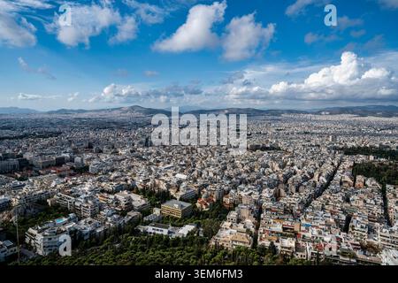 Ampia vista panoramica di Atene dal colle di Licabetto, in Grecia, che mostra i fitti edifici urbani, le montagne circostanti, le nuvole spettacolari e la Foto Stock