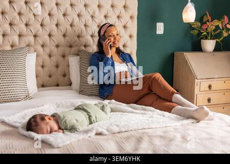 Mamma afro-americana con la figlia in camera da letto che parla al telefono e tiene appunti, copia spazio Foto Stock