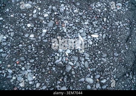Vista aerea ravvicinata della sabbia vulcanica nera e dei ciottoli arrotondati sulla spiaggia di Reynisfjara, nel sud dell'Islanda, creando un sorprendente monochrom naturale Foto Stock