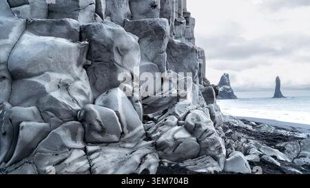 Ampia vista panoramica della spiaggia di sabbia nera di Reynisfjara nel sud dell'Islanda con spettacolari formazioni di colonne basaltiche in primo piano e l'iconica Reynis Foto Stock