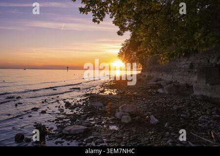Un suggestivo tramonto sulla costa rocciosa con acque calme, Lindau Island, Bodenseekreis, Germania Foto Stock