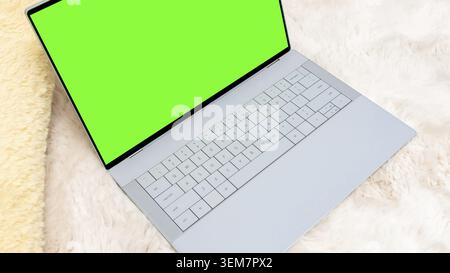 Mockup verde con un moderno laptop con schermo vuoto appoggiato su una morbida superficie in pelliccia, perfetto per presentazioni di design e display creativi Foto Stock