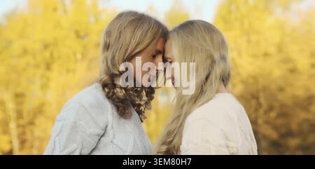 Ritratto di due donne felici, madre matura sorridente e figlia adulta che abbracciano nel parco autunnale Foto Stock