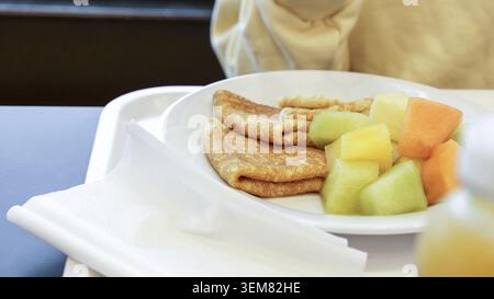 Deliziosa frutta fresca e pancake appena sfornati su piatto bianco. Colazione al ristorante Foto Stock