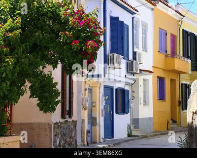 Una strada stretta fiancheggiata da edifici colorati, le loro facciate sono dipinte in tonalità pastello di bianco, blu, giallo e viola, con persiane in legno e. Foto Stock