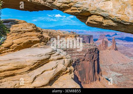 Il famoso Mesa Arch incornicia una vista panoramica del canyon e la lontana guglia di Washer Woman Arch nel Parco Nazionale di Canyonlands. Foto Stock