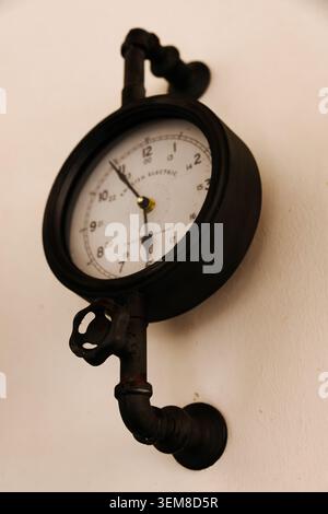 Primo piano di un orologio da parete industriale d'epoca realizzato con tubi, raccordi e componenti di valvole in metallo. Decorazioni interne in stile steampunk combinate Foto Stock