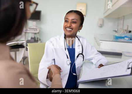 Allegra giovane medico nero donna che stringe la mano con il paziente Foto Stock