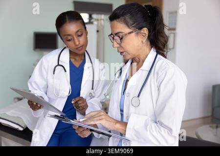 Due diverse donne che discutono dei dati dei pazienti Foto Stock