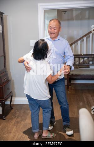 Coppia asiatica che balla e abbraccia in entrata, uomo maturo sorridente, donna anziana vicino, gabinetto Foto Stock
