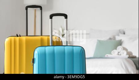 Colorful hard shell suitcases in modern hotel room with bed and towels, travel luggage for vacation, holiday accommodation, tourism and hospitality co Foto Stock
