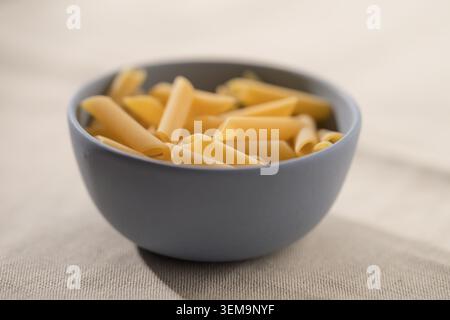 Asciugare la pasta da penne in un recipiente prima di cucinare Foto Stock