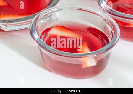 Gelatina di fragole appena versata con frutta fresca in vasetti di vetro singoli Foto Stock