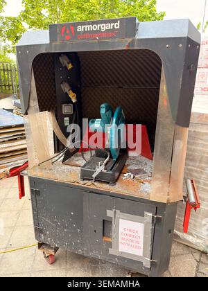 Stazione di lavoro per il taglio industriale con sega chiusa, pannelli in schiuma e segnaletica di sicurezza. Foto Stock