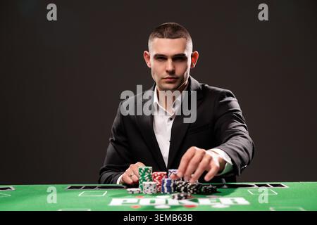 Bell'uomo barbuto sta giocando a poker seduto al tavolo nel casinò. Foto Stock