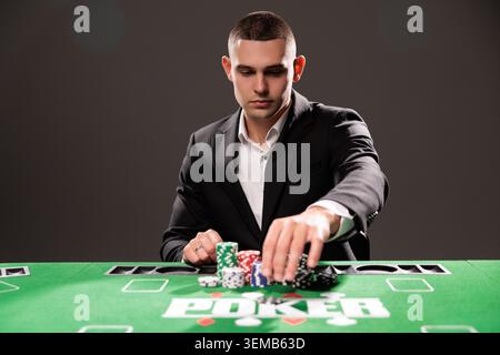 Bell'uomo barbuto sta giocando a poker seduto al tavolo nel casinò. Foto Stock
