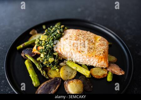Salmone arrosto con basilico e pesto di semi di girasole. Patate arrosto e asparagi Foto Stock