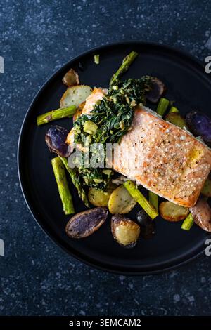 Salmone arrosto con basilico e pesto di semi di girasole. Patate arrosto e asparagi Foto Stock