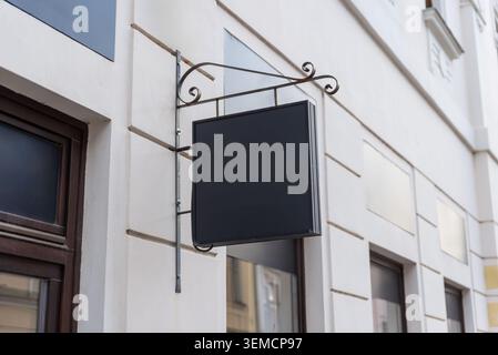 Cartello quadrato vuoto sospeso da una staffa decorativa in metallo su un edificio cittadino, adatto per il branding aziendale Foto Stock