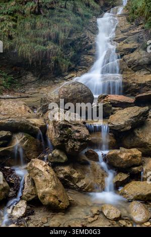 L'acqua scorre sulle rocce della cascata Nesselwang, circondata dalla natura verde a Bayern, Germania. Foto Stock