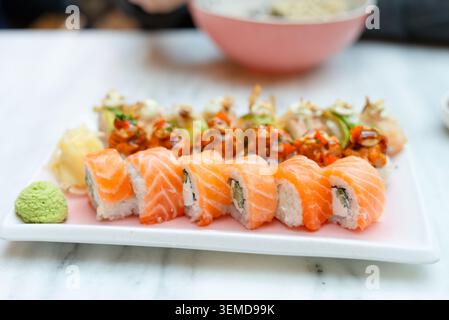 Elegante piatto di sushi su un tavolo di marmo bianco in un raffinato ristorante. Nigiri e sashimi di salmone freschi presentati su un piatto rettangolare. Ottima cucina giapponese con appetitoso stile gourmet Foto Stock