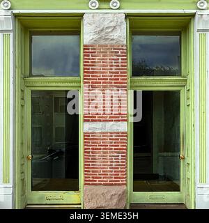 Ingresso incorniciato di verde che si apre all'interno di una facciata in mattoni rossi caratterizzata da grandi pannelli di vetro. Foto Stock