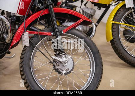 Vista ravvicinata dettagliata della ruota anteriore e del parafango rosso della motocicletta d'epoca. I dettagli cromati del motore e la ruota a raggi sono visibili, con un'informazione bianca Foto Stock