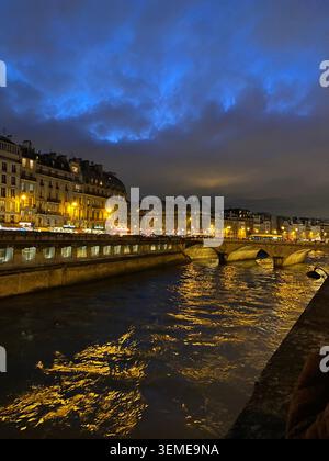 Vista notturna dell'Île de la Cité e della Senna a Parigi, Francia, con edifici illuminati lungo il fiume e riflessi del ponte. Foto Stock