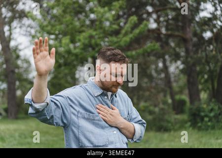 Uomo premuroso che prega all'aperto nel parco naturale Foto Stock