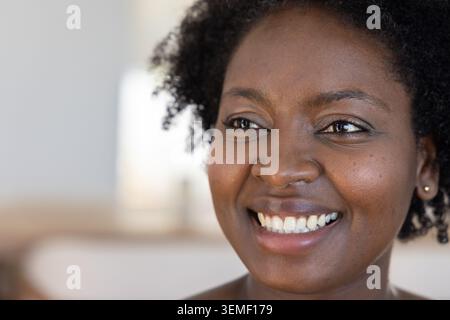 Donna afro-americana degli anni '30 sorridente, seduta in una lounge con un top casual che mostra un orecchino con borchie Foto Stock