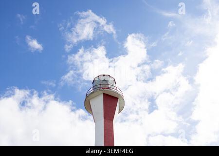 Foto ravvicinata della torre del faro di Cape Forchu vicino a Yarmouth, nuova Scozia, Canada, incorniciata contro un cielo blu vibrante con un bianco alla deriva Foto Stock