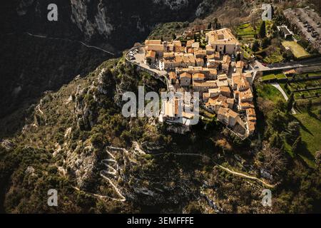Una fotografia verticale con un drone ad alto angolo che cattura l'architettura compatta di uno storico villaggio francese costruito su una ripida scogliera con un tortuoso pa Foto Stock