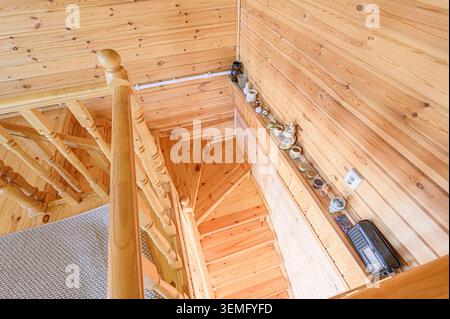 l'immagine ad angolo alto presenta scale in legno con corrimano in una stanza con pareti rivestite in legno. Piccoli oggetti decorativi sono su un ripiano Foto Stock