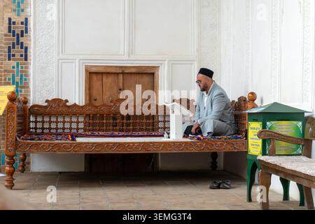 29 ottobre 2023. Samarcanda, Uzbekistan: Un uomo musulmano è seduto su una panchina nel cortile di una moschea per uomini. Un musulmano uzbeko legge il corano Foto Stock