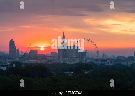 Il sole arancione si alza su Londra con il sole che sorge accanto allo Shard e al London Eye all'orizzonte nebbioso, Inghilterra, Regno Unito Foto Stock