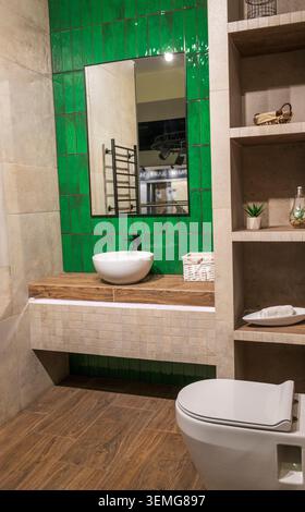 Bagno dal design contemporaneo con pareti in accento smeraldo e pavimento in legno Foto Stock