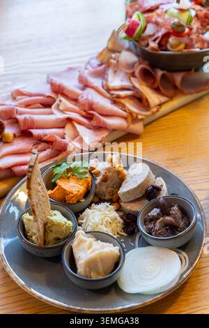 Tagliere di antipasti con salumi assortiti, vari patatine, salse e fette di cipolla fresche Foto Stock