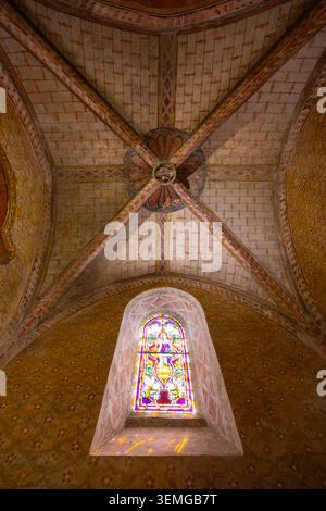 Vetrate colorate che proiettano una luce colorata su un'antica volta della chiesa dipinta Foto Stock