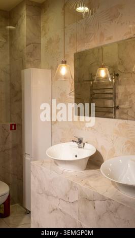 Bagno dal design contemporaneo con eleganti luci sospese e doppio lavabo Foto Stock